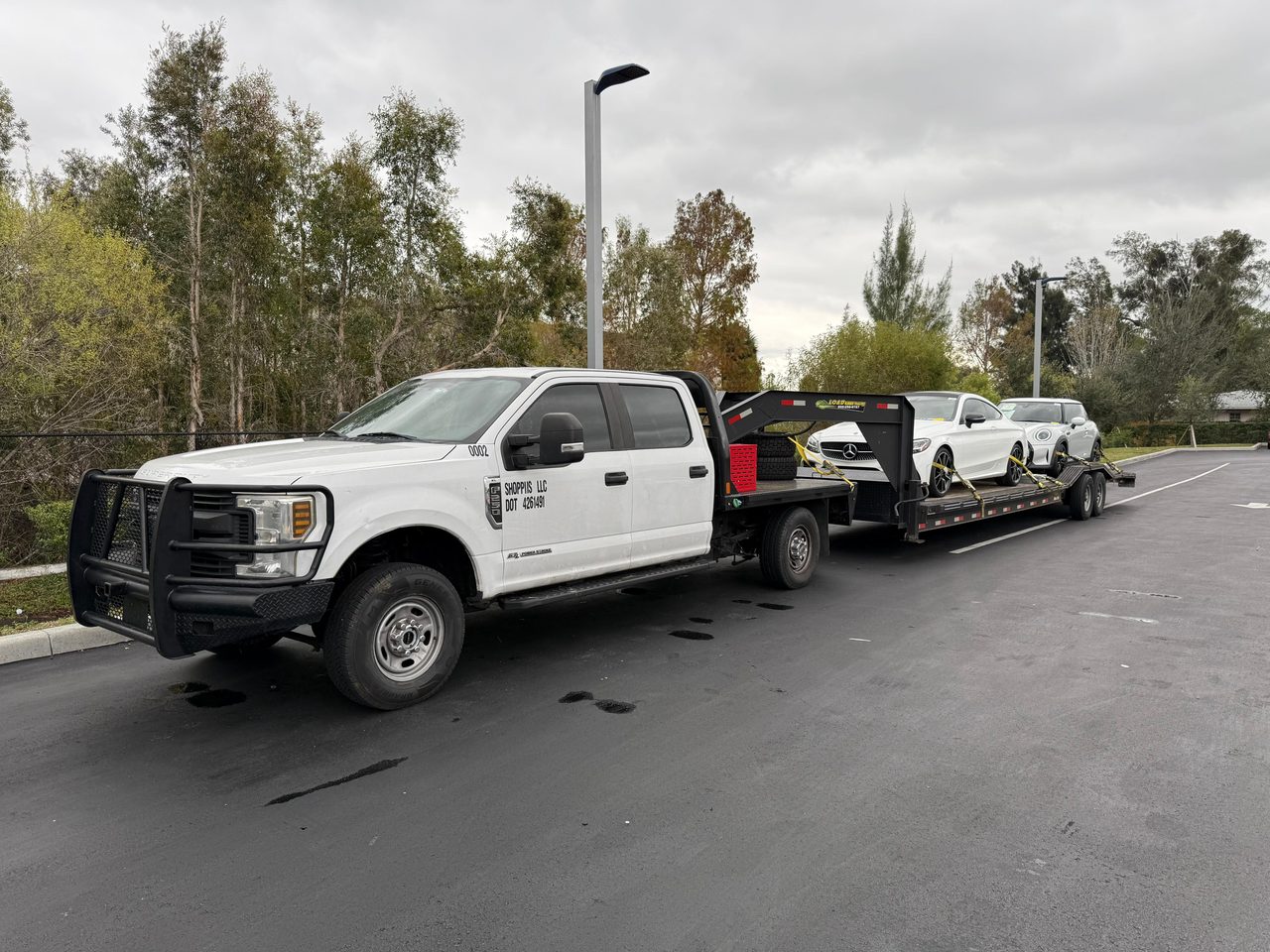 Shoppiis Ford F-250 and gooseneck trailer loaded with a Mercedes-Benz coupe and a Mini, ready for transport in Florida