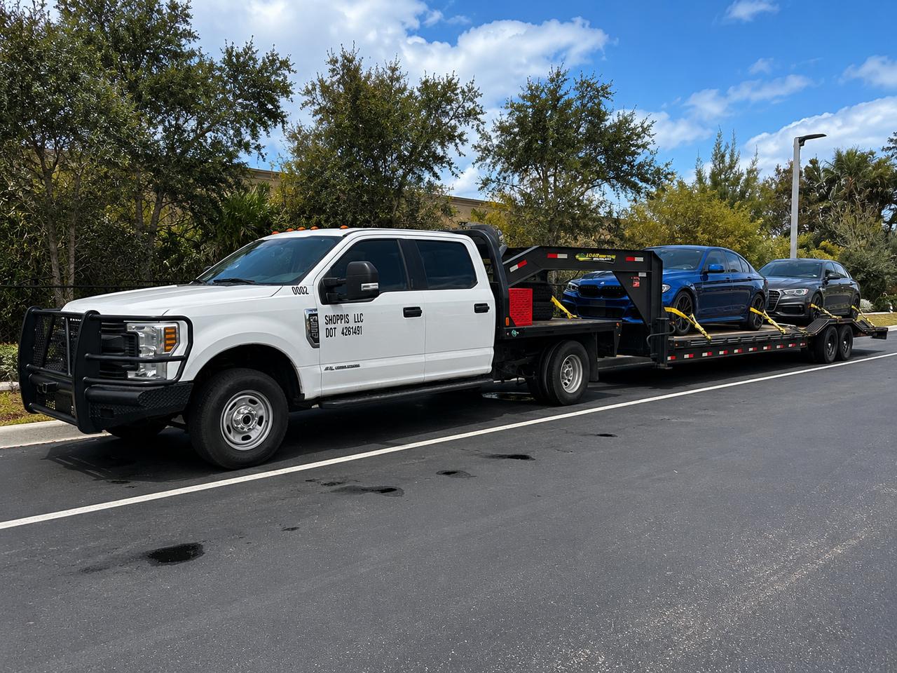 Shoppiis F-250 hauling a sports car and an SUV on the gooseneck trailer on a sunny Florida day